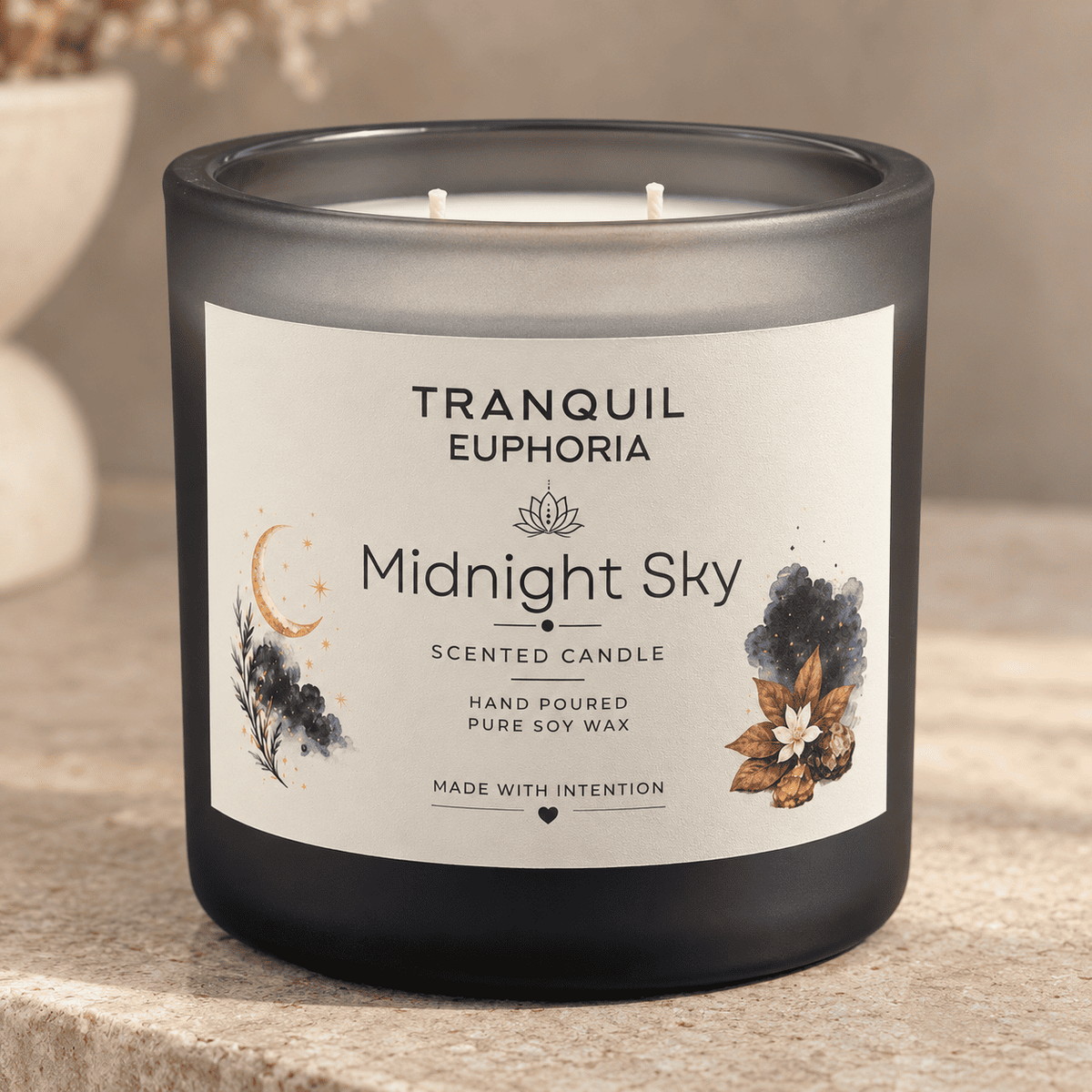 A frosted dark gray glass candle jar labeled 'Midnight Sky' by Tranquil Euphoria, with a cream label and botanical moon illustration, sitting on a stone surface.