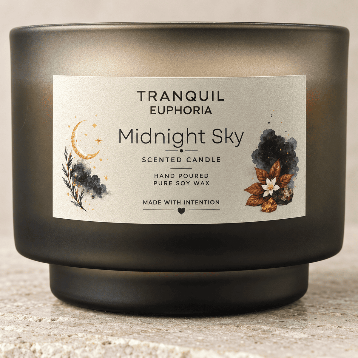 A Tranquil Euphoria 'Midnight Sky' scented candle in a dark, frosted glass jar with a cream-colored label featuring watercolor illustrations of a crescent moon and autumn leaves.