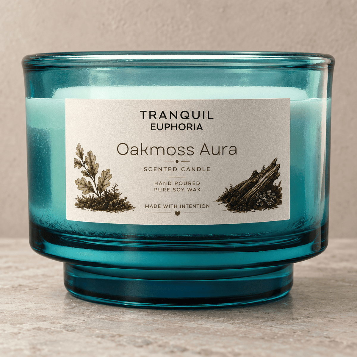 A teal blue glass scented candle jar with a white label reading 'Tranquil Euphoria Oakmoss Aura Scented Candle' on a neutral stone-textured background.