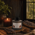 Spicy Tobacco round reed diffuser with six black fibre reeds beside lavender and a candle